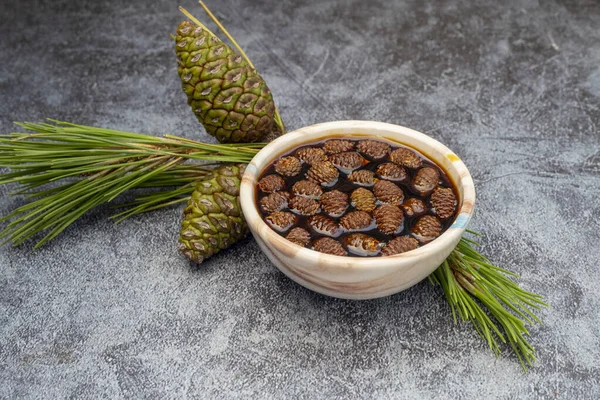 Young pine cones jam in glass bowl on gray marble background. Delicious jam with small pine cones.