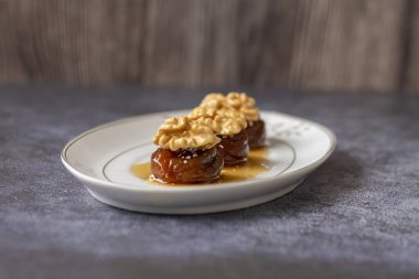 Geleneksel kurutulmuş incir tatlısıyla ceviz ve krema, şurupla pişirilir (Türkçe adı: Ceviz inciri tatlısı))