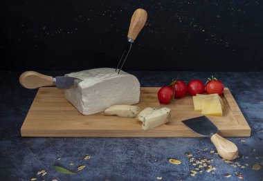 Siyah arka plan. Tahtada çeşitli peynirler.