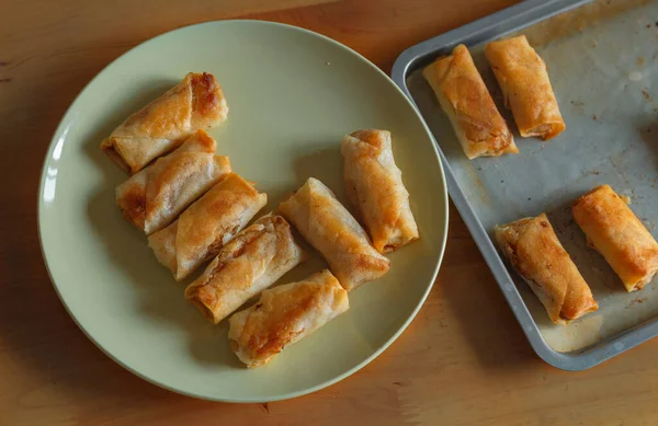 Freshly fried spring rolls are placed on a plate and in a baking dish. It looks golden and crispy and the texture is also crispy on the outside and tender on the inside, a delicious family snack.