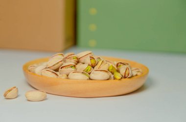 Resim yeşil bir arkaplan ve beyaz bir masanın üstüne yerleştirilmiş ahşap bir tepsiyi gösteriyor. Ahşap tabak fıstıklı çerezlerle dolu. Bu sağlıklı bir çerez ve en sevdiği sağlıklı yiyecektir..