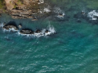 Deniz dalgaları kayaların üzerine düşüyor..