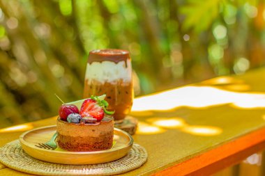 Buzlu çikolata - Tahta masada taze süt ve çikolata sosuyla karıştırılmış bir bardak koyu kakao ve bulanık arka plan. Yaz tatlı içeceği.