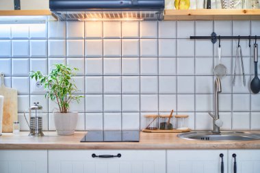 Beyaz duvar kiremitleri olan modern, rahat çatı katı mutfağı.                     