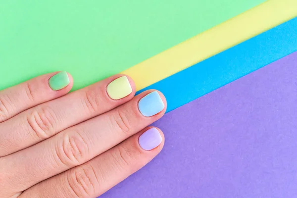 Female fingers with bright summer nails on a colorful background close up. Top view
