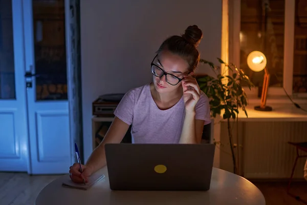 여자가 안경을 일하는 랩탑에서 일하는 노트북에 쪽지를 적는다 — 스톡 사진