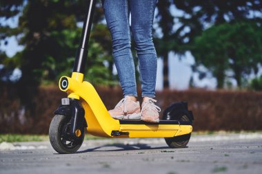 Şehirde hızlı hareket etmek için elektrikli scooter kullanan bir kadın.          