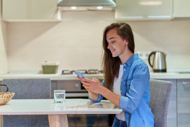 Çevrimiçi sohbet ve gezmek için akıllı telefon kullanan çekici, sıradan, mutlu, modern bir genç kız.