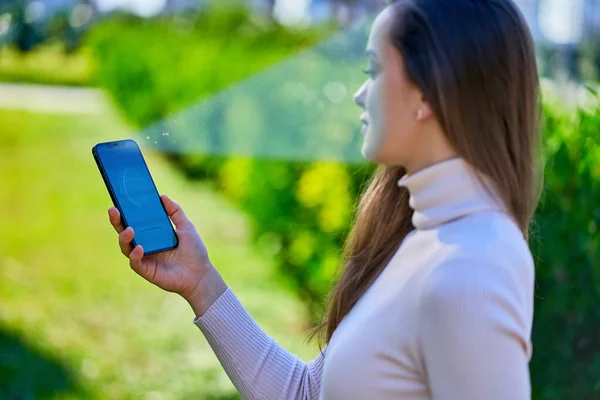 여성들은 시스템을 사용하여 새로운 스마트폰에 얼굴을 스캔하여 인식을 밖에서 전화를 — 스톡 사진