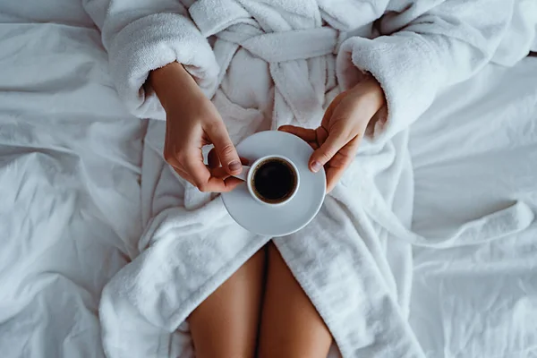 在宾馆房间舒适舒适的卧室里 穿着浴衣的懒惰女人躺在床上 享受着芬芳的咖啡杯 简单的生活方式 新一天的开始 — 图库照片