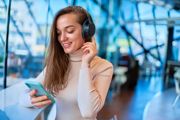 Junge Fröhliche Fröhliche Frau Trägt Drahtlose Kopfhörer Mit Smartphone Café — Stockfoto