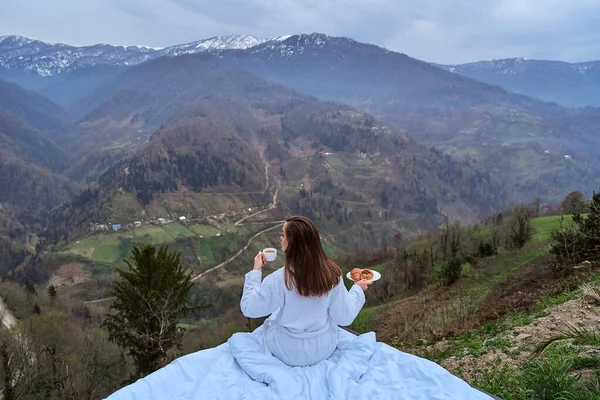 早朝の朝食を楽しむバスローブを着た女性旅行者とベッドでリラックスしている間の山の景色 人が幸福と自由を感じるとき 静かでさまよう欲望の概念の瞬間 — ストック写真