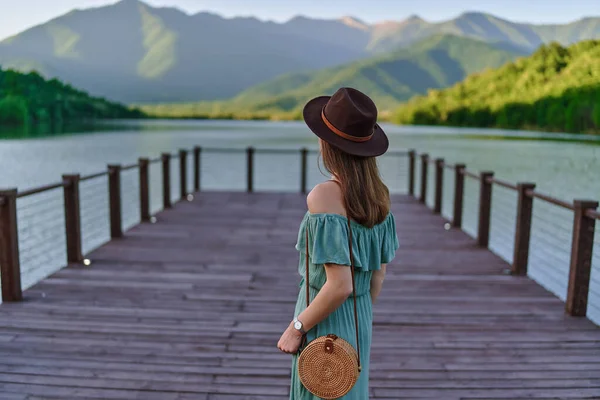 旅行者の女の子だけで桟橋に立って 湖や山を見つめている 美しい自由の瞬間と自然の中で穏やかな平和的な雰囲気 バックビュー — ストック写真