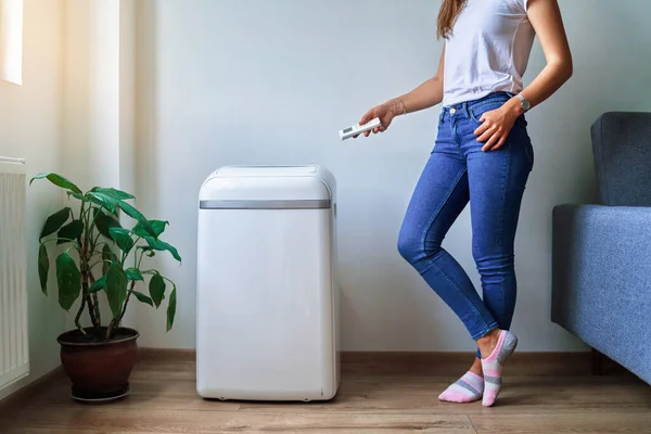 stock image Woman regulates the cooling temperature of the air conditioner at home the remote control in hot summer weather. Fresh and clean air at home 