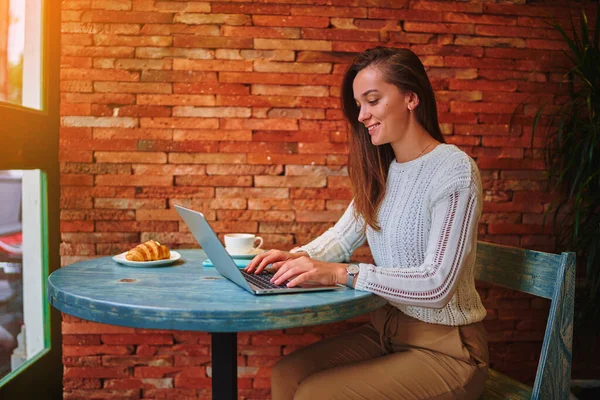 カフェでオンラインでリモートで作業中にラップトップキーボード上のかわいい若いスマート現代のコピーライターフリーの女の子のタイプ — ストック写真