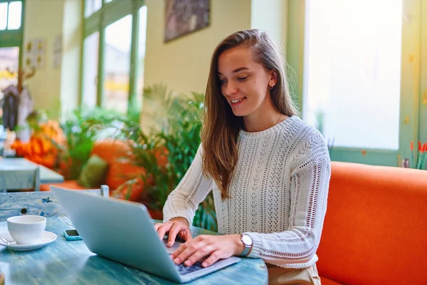 かわいい若い幸せな笑顔の肖像画スマート現代のコピーライターフリーランスの女の子は カフェでリモートでオンラインで作業中にノートパソコンのキーボードを入力 — ストック写真