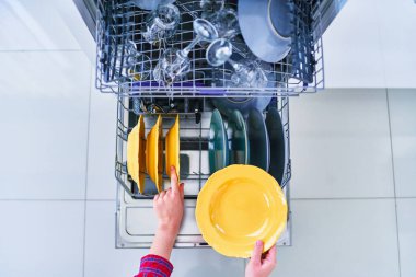 Beyaz bir ev mutfağında parlak temiz tabakları olan bulaşık makinesini aç.
