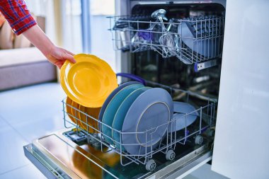 Ev hanımı modern bulaşık makinesini ev mutfağında bulaşık yıkamak için kullanıyor 