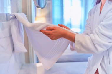 Woman drying her hands with white cotton soft towel in bathroom