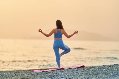 Bedava sükunet, huzur ve mutluluk dolu spor yapan kadının sahilde yoga egzersizi yapması. Zihinsel bakım ve sağlıklı alışkanlıklar