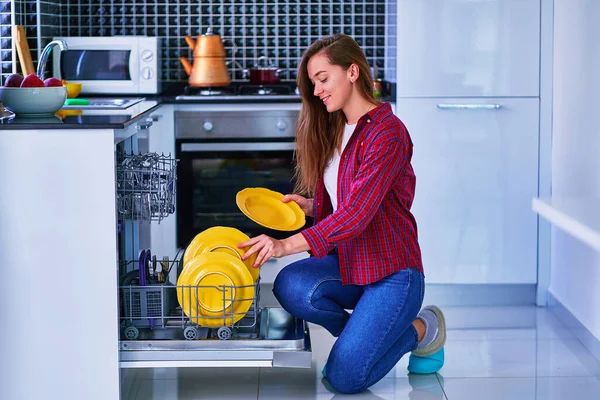 年轻快乐的女人满意地微笑着可爱的家庭主妇 她用现代洗碗机在家里的白色厨房洗碗和洗眼镜 — 图库照片