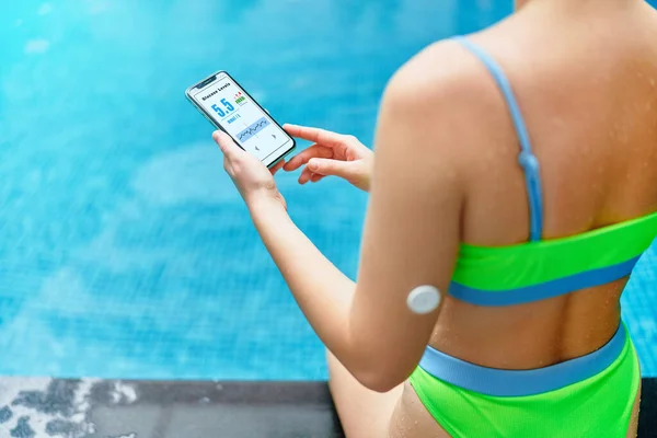 Active athletic fitness diabetic patient monitoring glucose level with remote sensor while training at swimming pool. Smart medical technology in diabetes treatment. Copy space