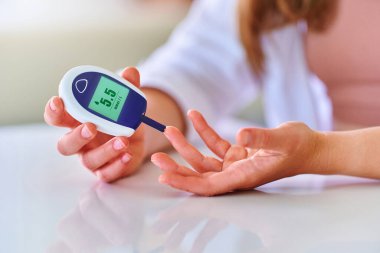 Kan seviyesini ölçmek ve izlemek için glikoz ölçer kullanan bir kadın. Sağlık ve mellitus diyabet tedavisi 