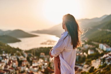 Sakin, düşünceli, düşünceli bir kadın gün batımındaki güzel manzaraya bakar. 