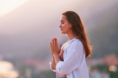 Umut dolu, dingin bir kadın, gün batımında dua eden ellerle yalnız başına meditasyon yapar. Rahatlama stresi ve sağlıklı zihinler 