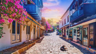 Eski renkli sokak manzarası. Türkiye 'nin Kas kentinde ahşap mavi balkonları ve pembe çiçekleri olan beyaz evler 