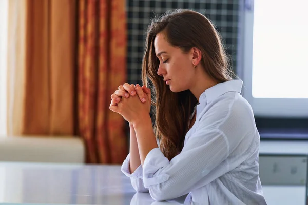 孤独而平静的女性信徒坐在桌旁 独自在家中祈祷 默默向上帝祈祷 寻求支持和帮助 相信最美好的事物 — 图库照片