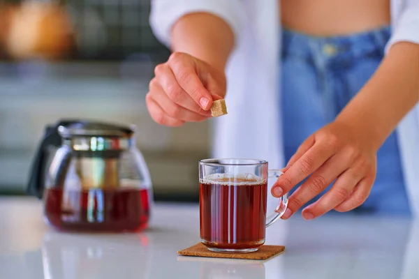 女性追加杖黒糖キューブへ黒茶にホームキッチン — ストック写真