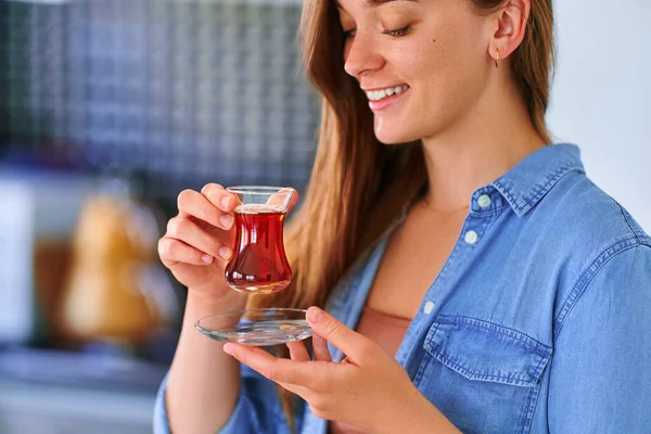 美しい満足笑顔幸せな女性は自宅のキッチンで伝統的なトルコ茶を飲む — ストック写真