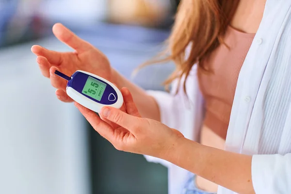 Female using glucose meter for measuring and monitoring blood level. Healthcare and mellitus diabetes treatment