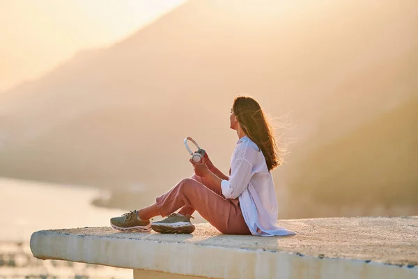 幸せな女性が上に座って 日没時に美しい景色で穏やかな音楽を聴くのを楽しんでインスピレーションを得ました 救済のストレスと健康的な心 — ストック写真