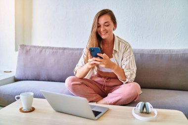 Dertsiz tasasız, mutlu ve mutlu bir genç kız ev içi telefon kullanıyor. 