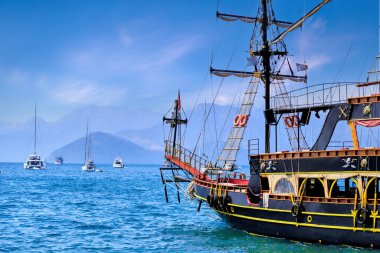 Ahşap turistik korsan gemisi mavi bir Akdeniz gölünde demirlemiş.