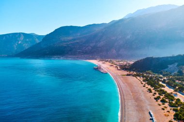 Yazın güneşli bir günde dağlı, kumlu plajlı ve tekneli Akdeniz koyunun havadan görünüşü. Mavi Göl 'ün İHA fotoğrafı Oludeniz, Türkiye