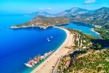 Yazın güneşli bir günde dağlı, kumlu plajlı ve tekneli Akdeniz koyunun havadan görünüşü. Mavi Göl 'ün İHA fotoğrafı Oludeniz, Türkiye