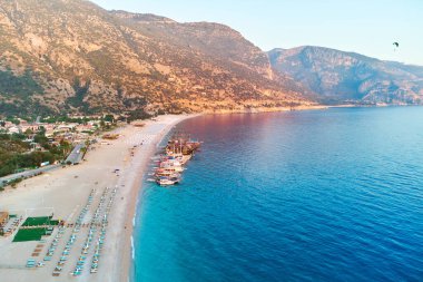Yazın güneşli bir günde dağlı, kumlu plajlı ve tekneli Akdeniz koyunun havadan görünüşü. Mavi Göl 'ün İHA fotoğrafı Oludeniz, Türkiye