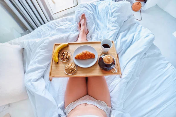 目覚めの女性は快適な怠惰な居心地の良い朝にベッドで朝食をお楽しみください — ストック写真