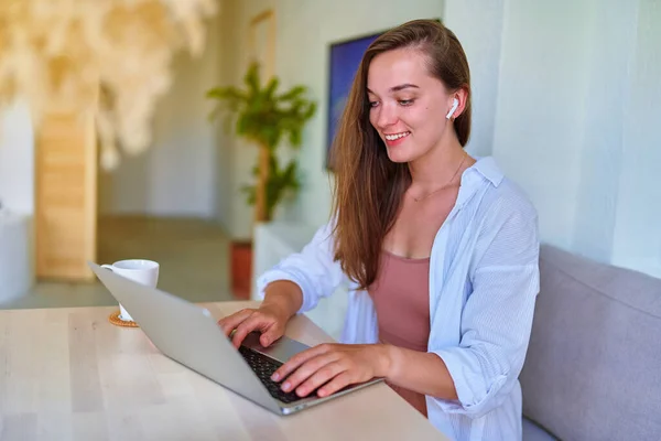 소녀는 집안에서 컴퓨터를 사용하여 현대인 미소짓는 귀여운 소녀를 기뻐하고 — 스톡 사진