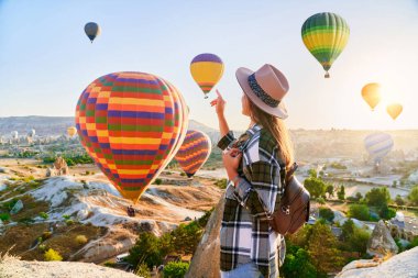 Türkiye 'nin Goreme kentinde kız gezginler tatil yapıyor. Güneş doğarken uçan balonlarla muhteşem Kapadokya, Anadolu