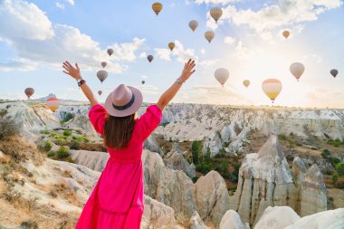 Kolları açık gezen kız gezgin Goreme, Türkiye 'de güzel bir varış yeri. Güneş doğarken uçan balonlarla muhteşem Kapadokya, Anadolu