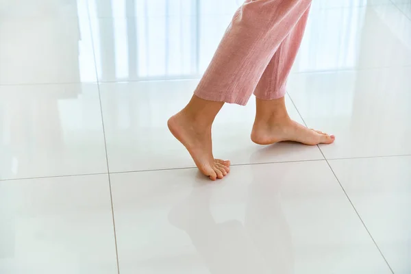 Female barefoot legs on heated warm floor in living room at home