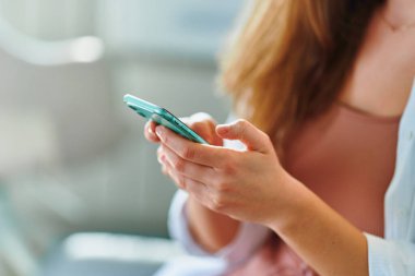 Kadın elleri telefonu tutuyor.