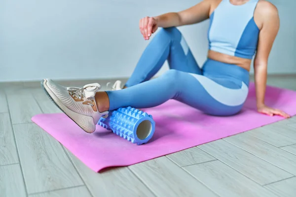 Woman using roller for self muscle massage