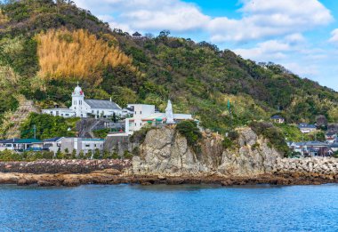 Nagasaki, Kyushu - 13 Aralık 2022: Nagasaki Körfezi 'ndeki Kaminoshima Katolik Kilisesi' nin önünde duran beyaz Bakire Meryem heykeliyle Kamino adasının kıyıları.