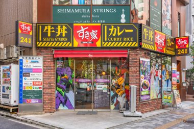 Tokyo, akihabara - 29 Mart 2021: Pencereleri ünlü Japon mangası ve anime Neon Evangelion 'un karakterleri ve robotlarının yer aldığı çıkartmalarla süslenmiş fast food Sukiya restoranı.