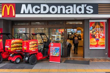 Tokyo, Japonya - 11 Nisan 2023: Japon Honda Gyro Canopy McDelivery için kullanılan üç tekerlekli motosiklet McDonalds 'a park edilmiş ve içinde One Piece anime ve manga karakterleri olan bir reklam posteri.